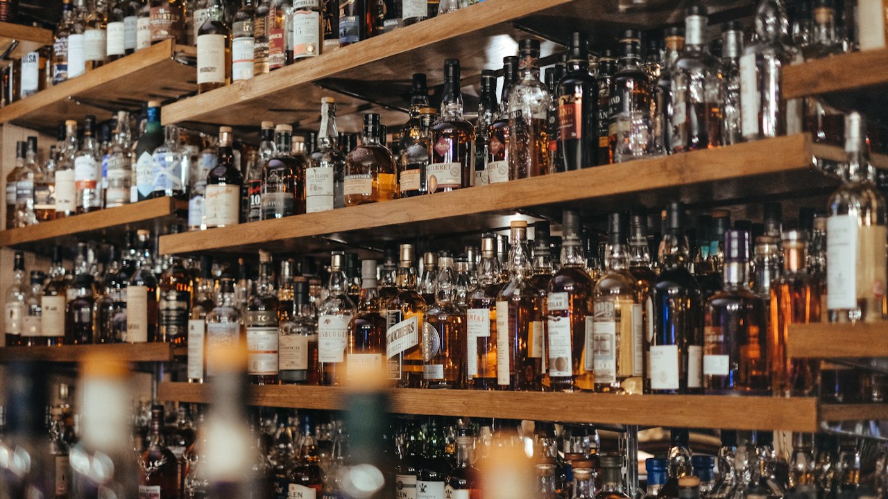 A long wall of backlit bottle shelving in warm amber light